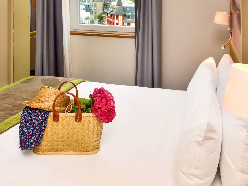 a basket of flowers on a bed in a hotel room at Mercure Granville Le Grand Large in Granville