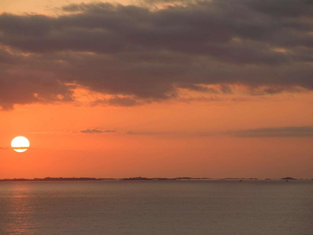 a sunset over the water with the sun in the sky at Mercure Granville Le Grand Large in Granville