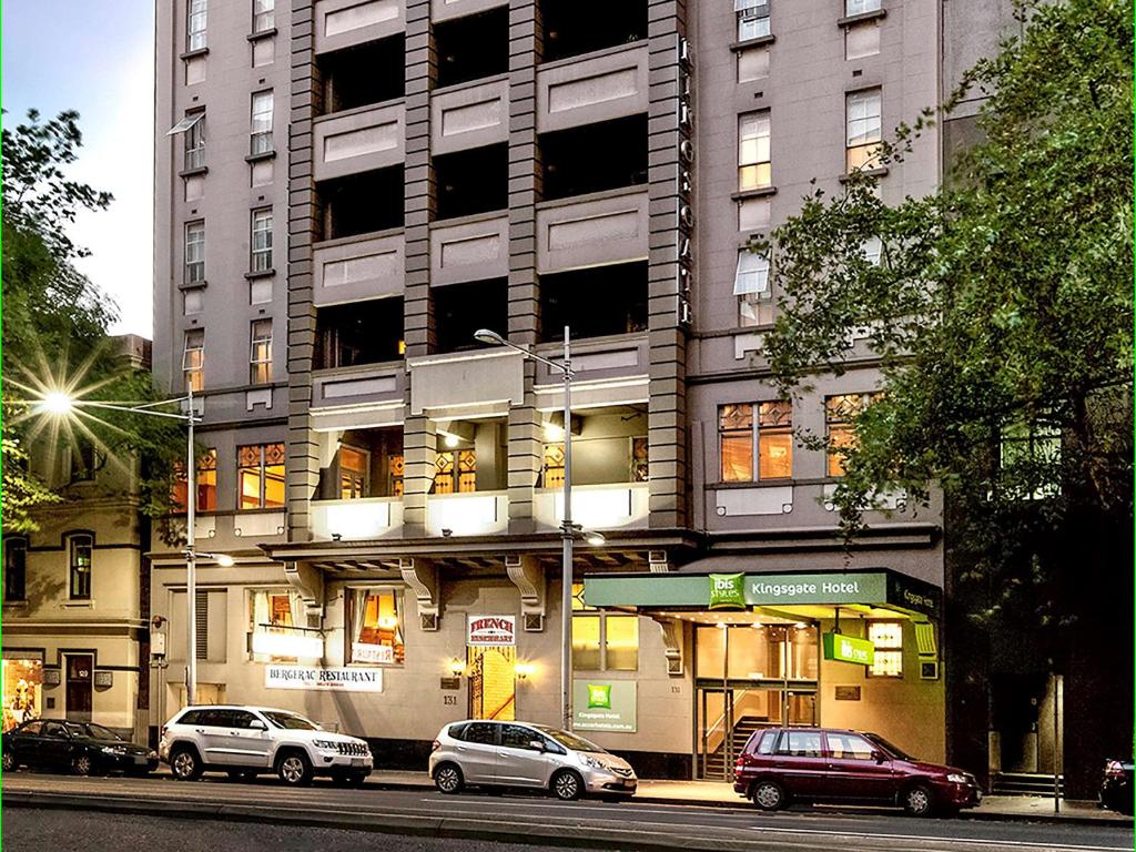 um edifício alto com carros estacionados em frente em ibis Styles Kingsgate Hotel em Melbourne