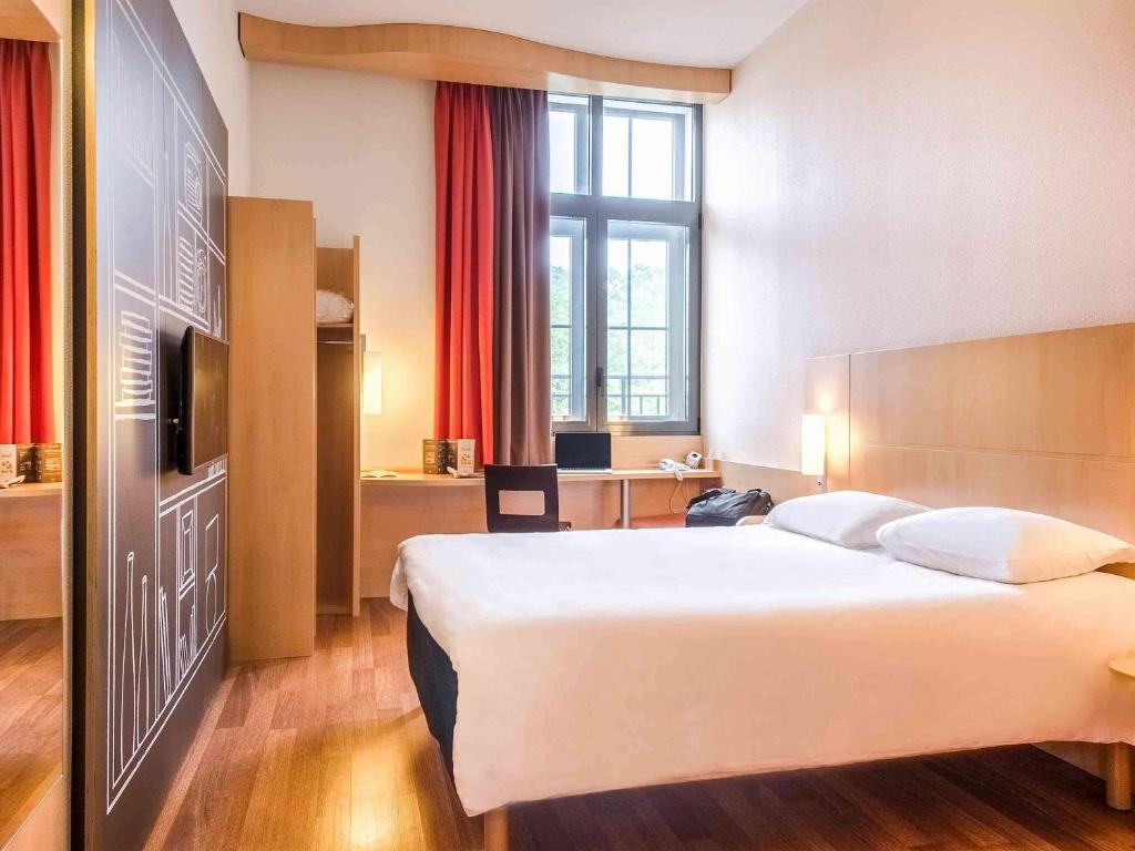 a hotel room with a large bed and a desk at Ibis Sarlat Centre in Sarlat-la-Canéda