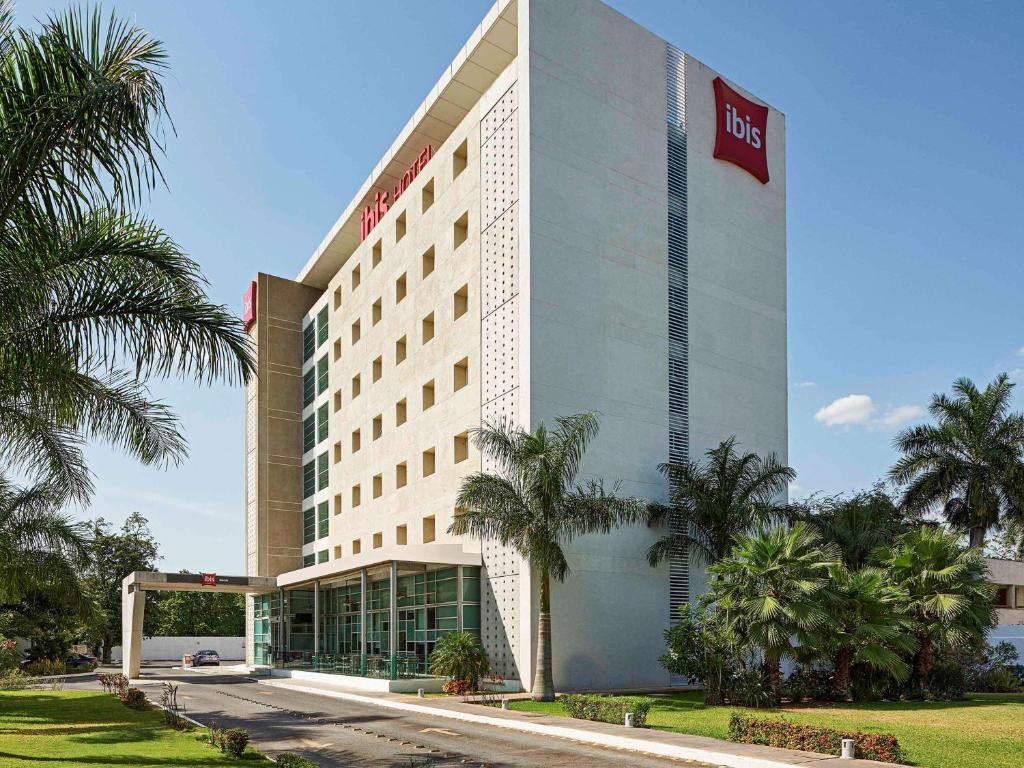 a hotel building with palm trees in front of it at Ibis Merida in Mérida