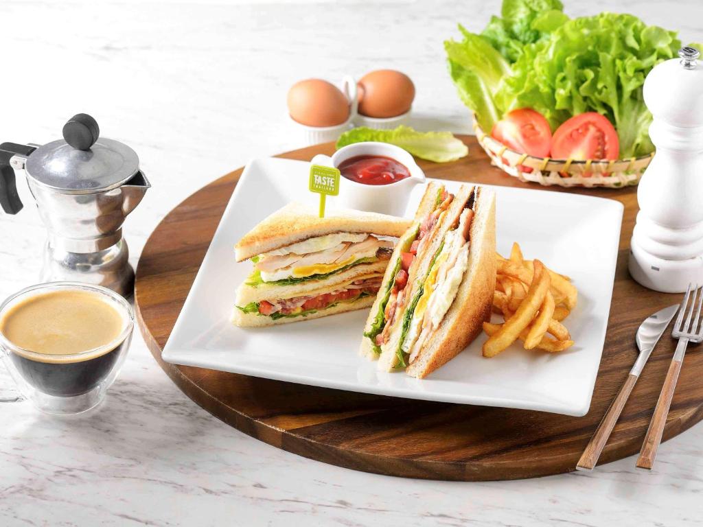 a plate with a sandwich and french fries on a table at Ibis Phuket Patong in Patong Beach