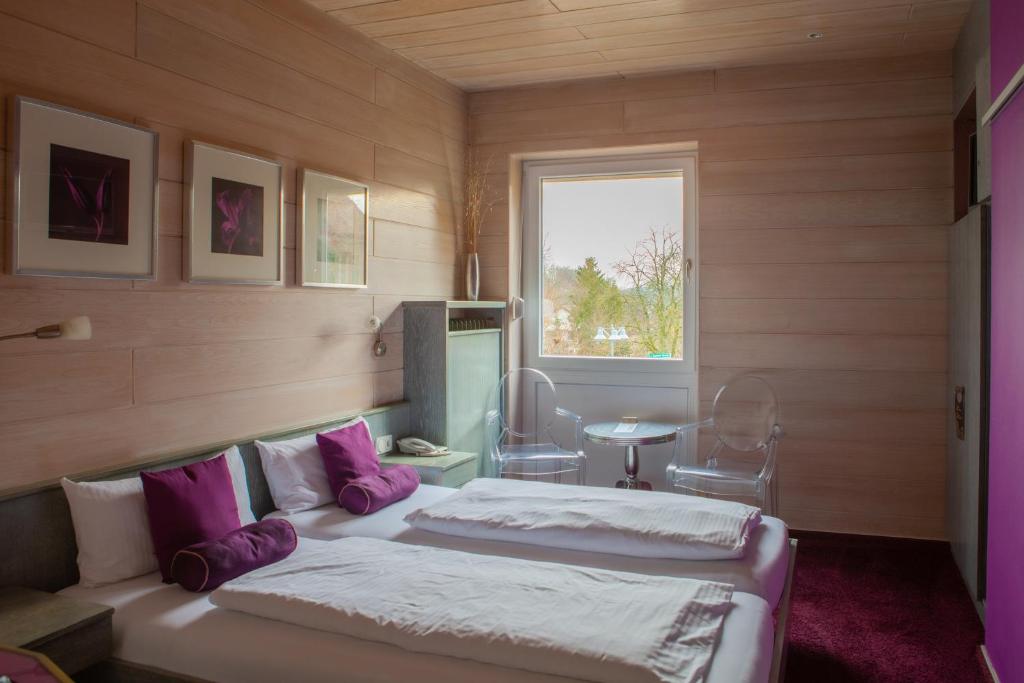 een slaapkamer met 2 bedden, een tafel en een raam bij Hotel Kolb in Zeil