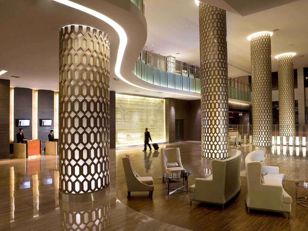 Novotel Bangka Hotel & Convention Center في بانغكال بينانغ: لوبي فيه اعمدة وكراسي في مبنى