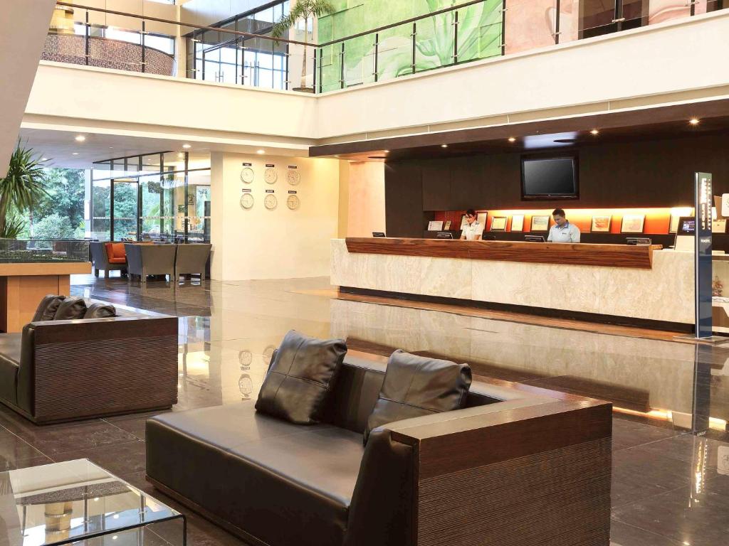 a lobby with a couch and a tv in a building at Novotel Manado Golf Resort & Convention Center in Manado