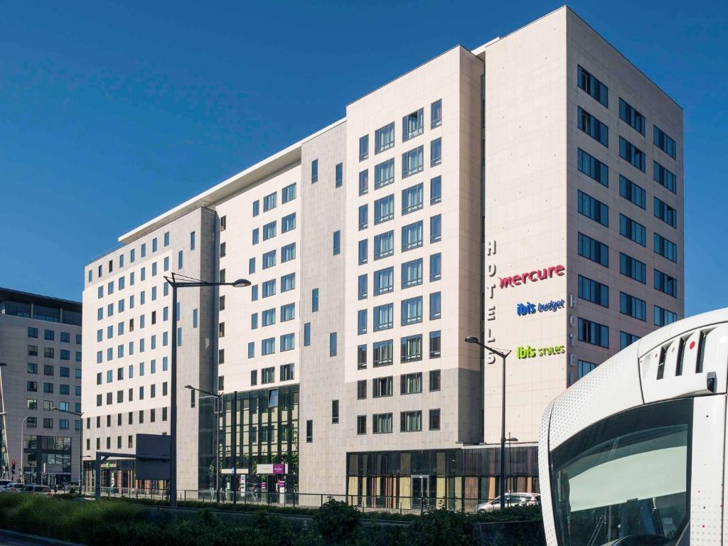 un grand bâtiment blanc avec un bus devant lui dans l'établissement Mercure Lyon Centre - Gare Part Dieu, à Lyon