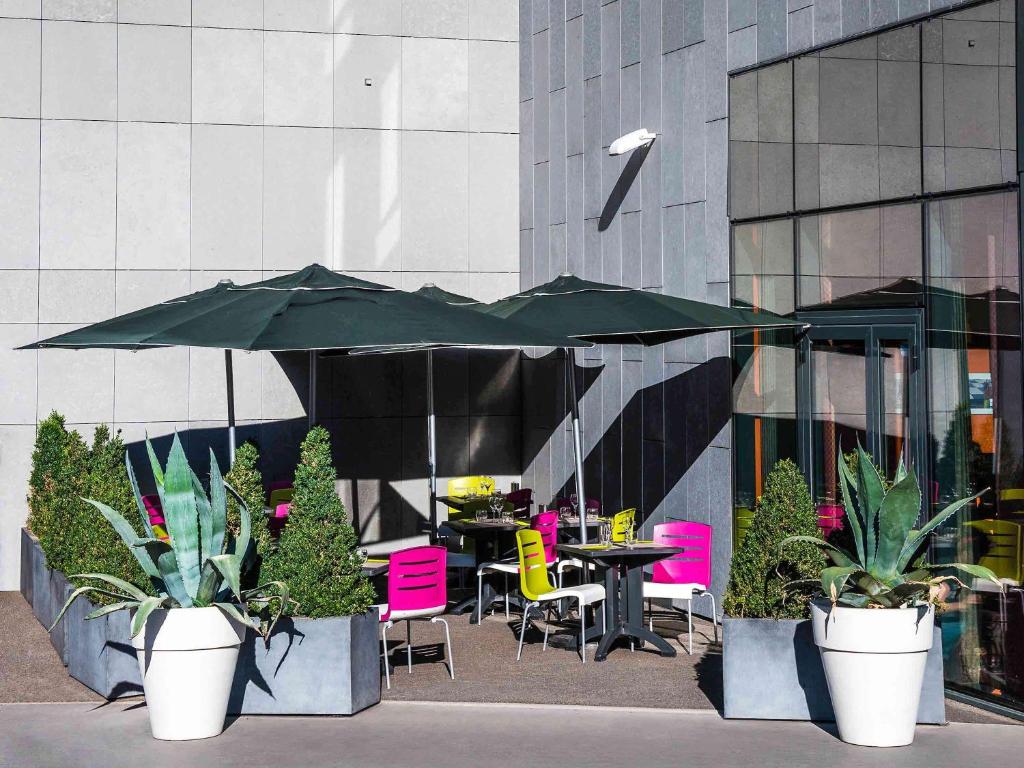 une terrasse avec une table, des chaises et des parasols dans l'établissement Ibis Styles Lyon Centre - Gare Part Dieu, à Lyon