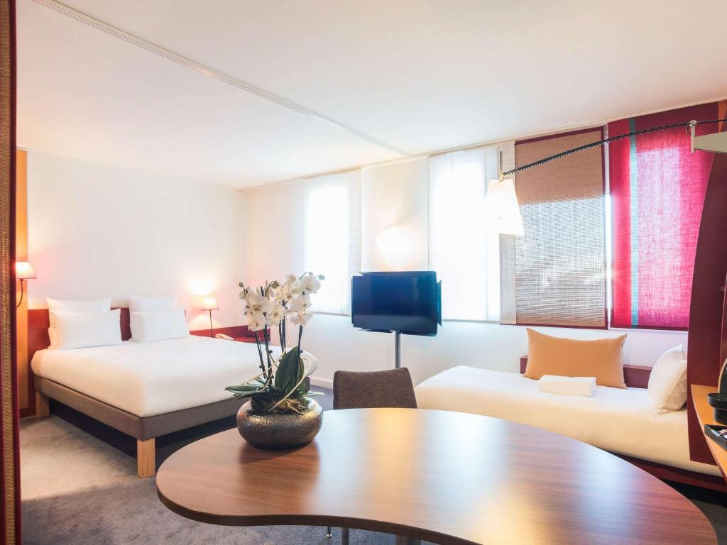 Novotel Suites Reims Centre في رانس: غرفة في الفندق مع أريكة وطاولة