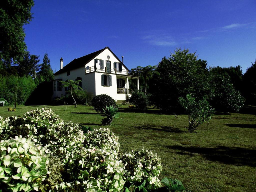 a white house in a field with some flowers at Vila Joaninha in Santo da Serra