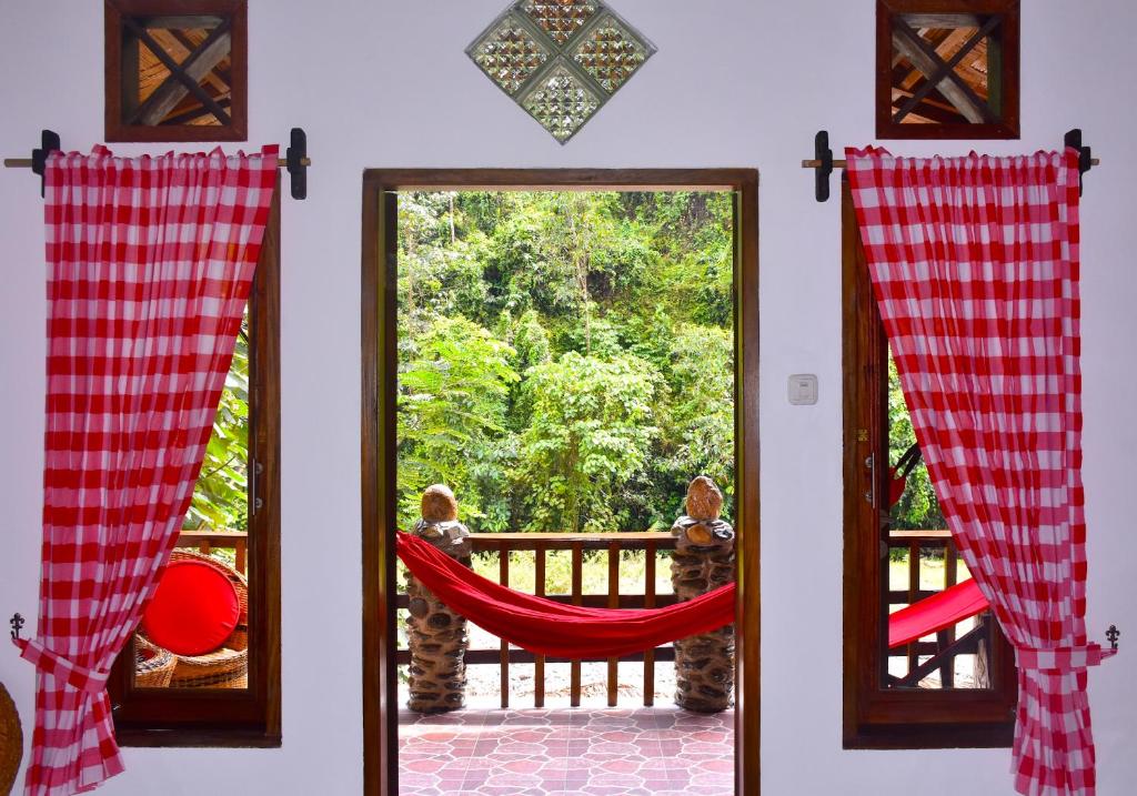 a cat sitting in a hammock looking out a window at The Hangout@ EcoTravel in Bukit Lawang