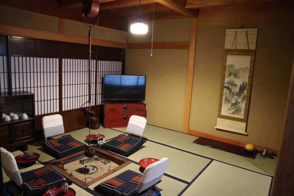 een woonkamer met een tafel en stoelen en een televisie bij Yoshiki Stay in Furukawachō