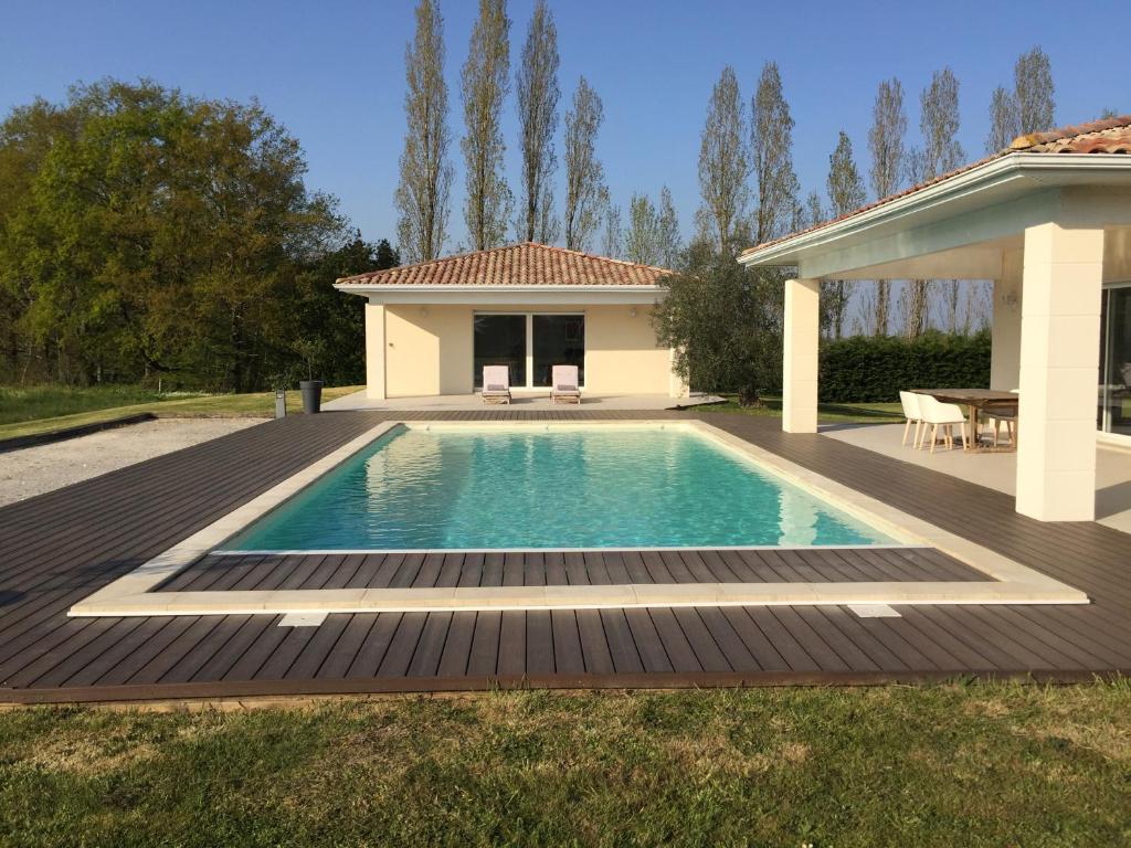 uma piscina com um deque e uma casa em Chambre d'hôtes Ama em Pompignac