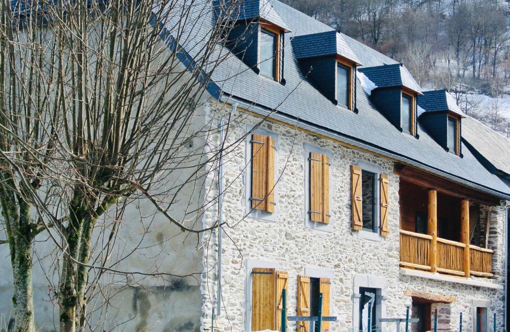 a white building with orange windows and a tree at Les Granges de Clarabide in Loudenvielle