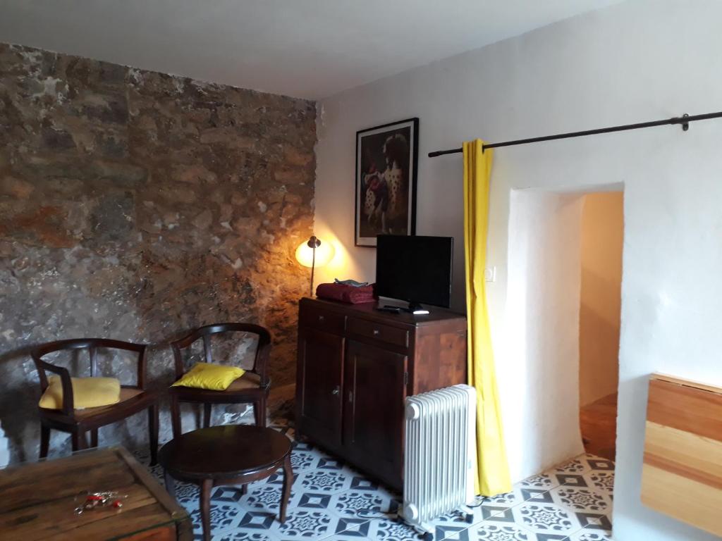 ein Wohnzimmer mit einem TV, einem Tisch und Stühlen in der Unterkunft Caraussane caractère terrasse sur jardin et wifi via fibre en coeur de ville in Sète