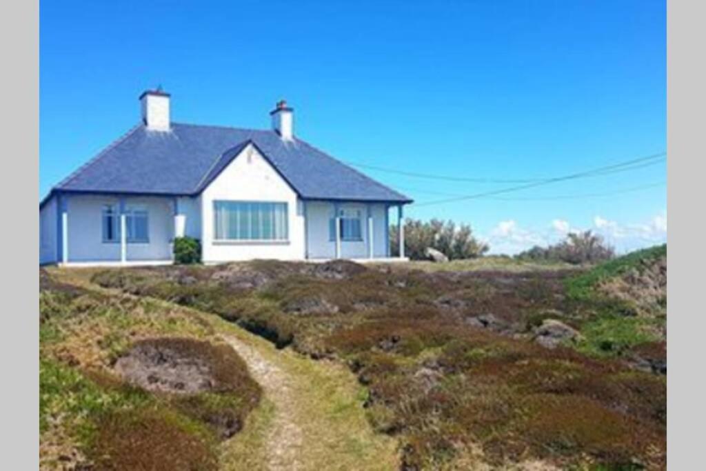 a white house sitting on top of a hill at THE CREST- 4 BED SEA VIEW PROPERTY -TREARDDUR BAY in Trearddur