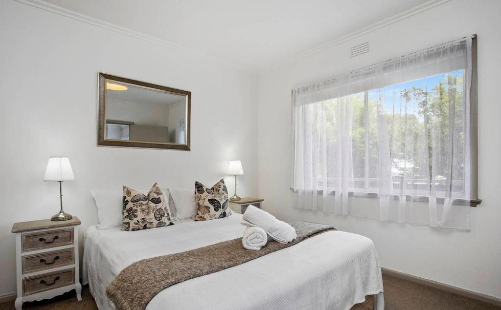 two beds in a bedroom with a mirror and a window at Geelong Serviced Apartments in Geelong