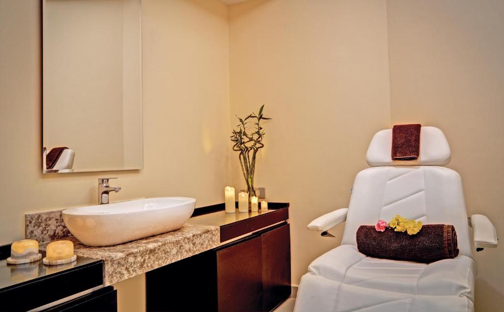 une salle de bain avec un lavabo blanc et une chaise dans l'établissement Cleopatra Luxury Resort Sharm El Sheikh, à Charm el-Cheikh