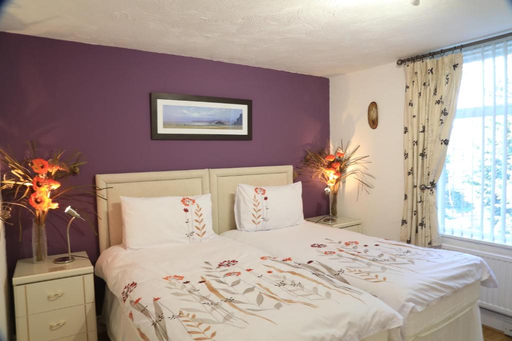 1 dormitorio con paredes moradas y 1 cama con almohadas en La Suisse Serviced Apartments, en Mánchester