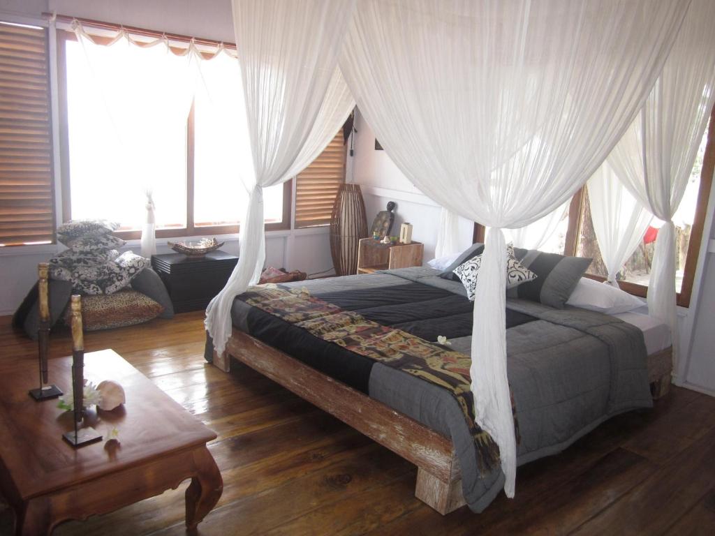 a bedroom with a bed with curtains and a table at Pondok Wisata Pantai Cemara in Mondu