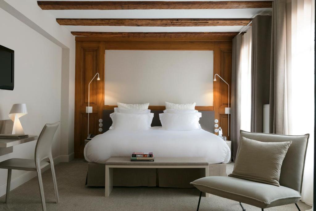 
a hotel room with a bed and a chair at Relais & Châteaux La Maison Des Têtes in Colmar
