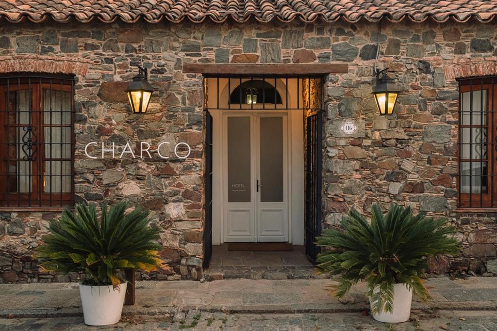 a stone building with a white door and two potted plants at Charco Hotel in Colonia del Sacramento