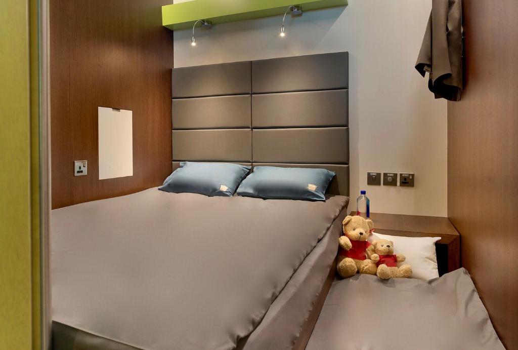 a large bed with a teddy bear sitting on it at sleep 'n fly Sleep Lounge, SOUTH Node - TRANSIT ONLY in Doha