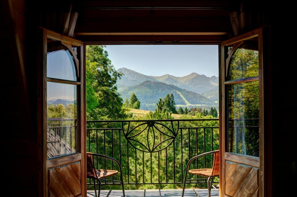 an open door to a balcony with a view of mountains at Apartamenty Willa Olsza - wood house & mountain view in Zakopane