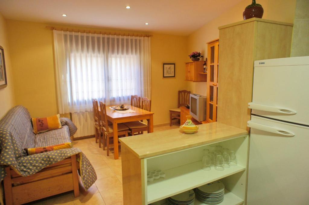 eine Küche und ein Wohnzimmer mit einem Kühlschrank und einem Tisch in der Unterkunft Ca La Paletes in Cornudella de Montsant