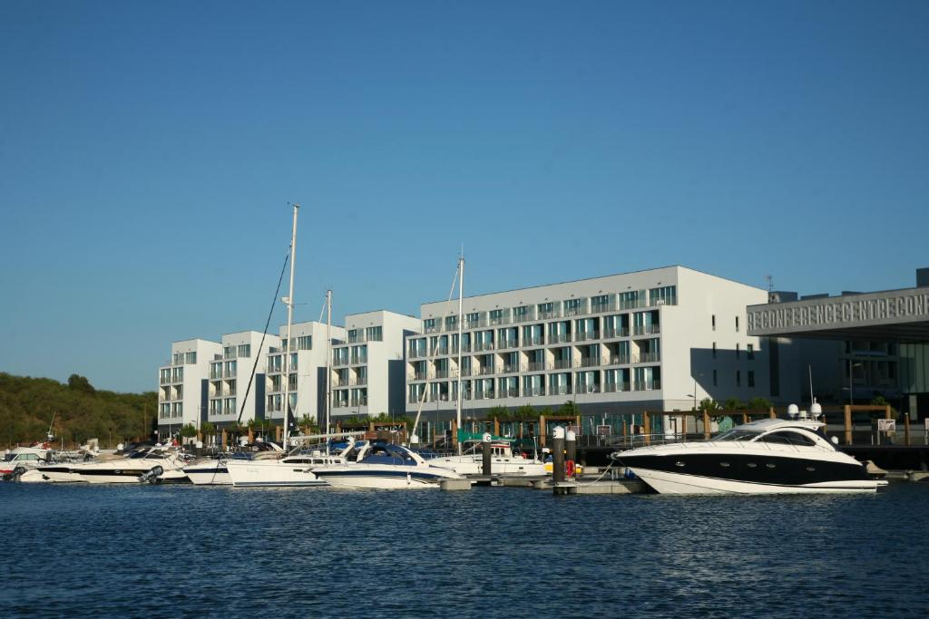 eine Gruppe von Booten, die in einem Hafen mit einem Gebäude angedockt sind in der Unterkunft Troia Residence by The Editory - Apartamentos Marina in Troia