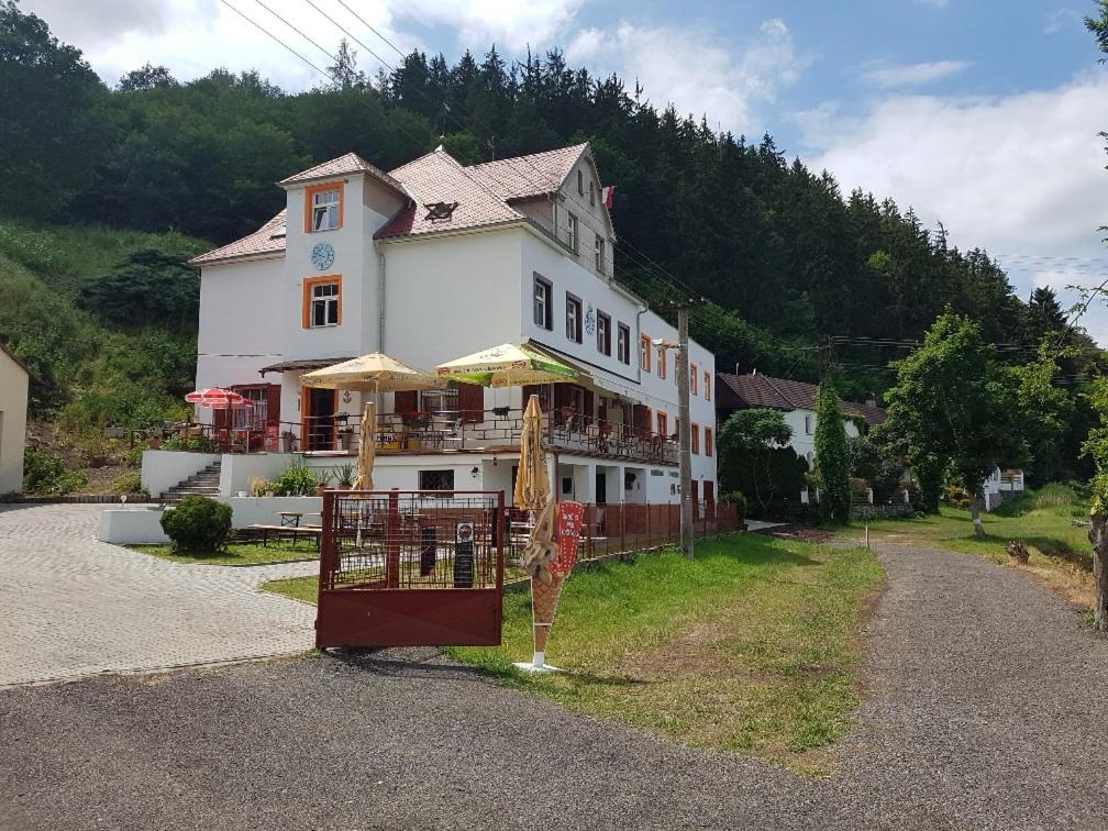 a large white building with tables and umbrellas at Penzion Na Prachárně in Kladruby