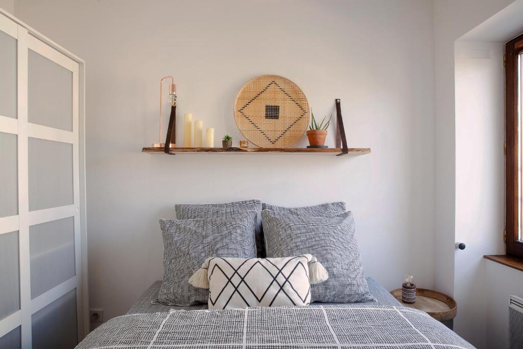 a bedroom with a bed with gray pillows and a shelf at Duplex lumineux 2 chambres centre zone piétonne in Valence