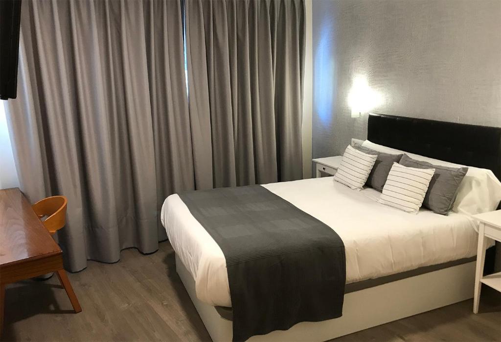 Habitación de hotel con cama con sábanas y almohadas blancas en HOTEL DEL NORA, en Noreña