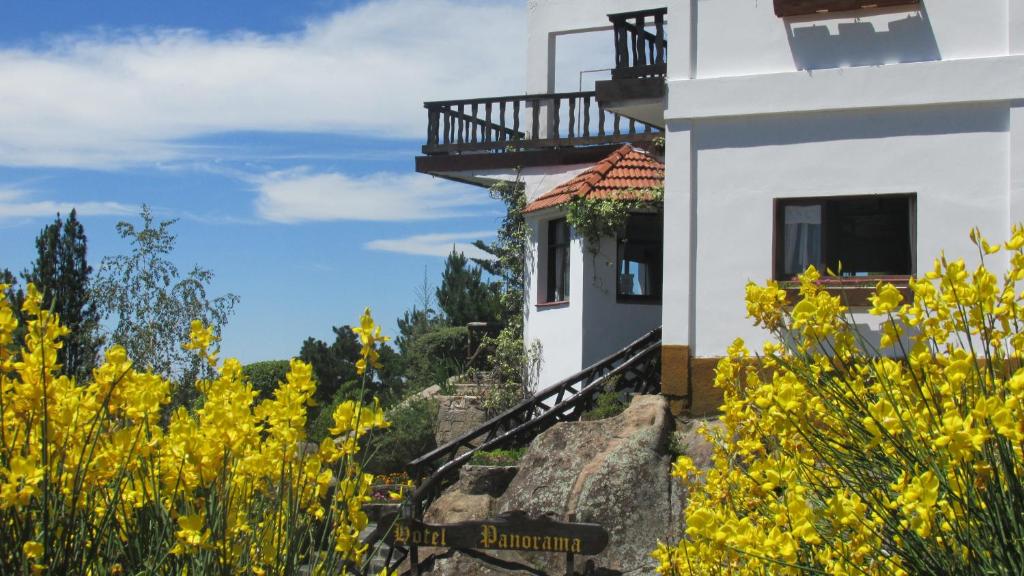 un edificio blanco con balcón en un campo de flores amarillas en Hotel Panorama en La Cumbrecita