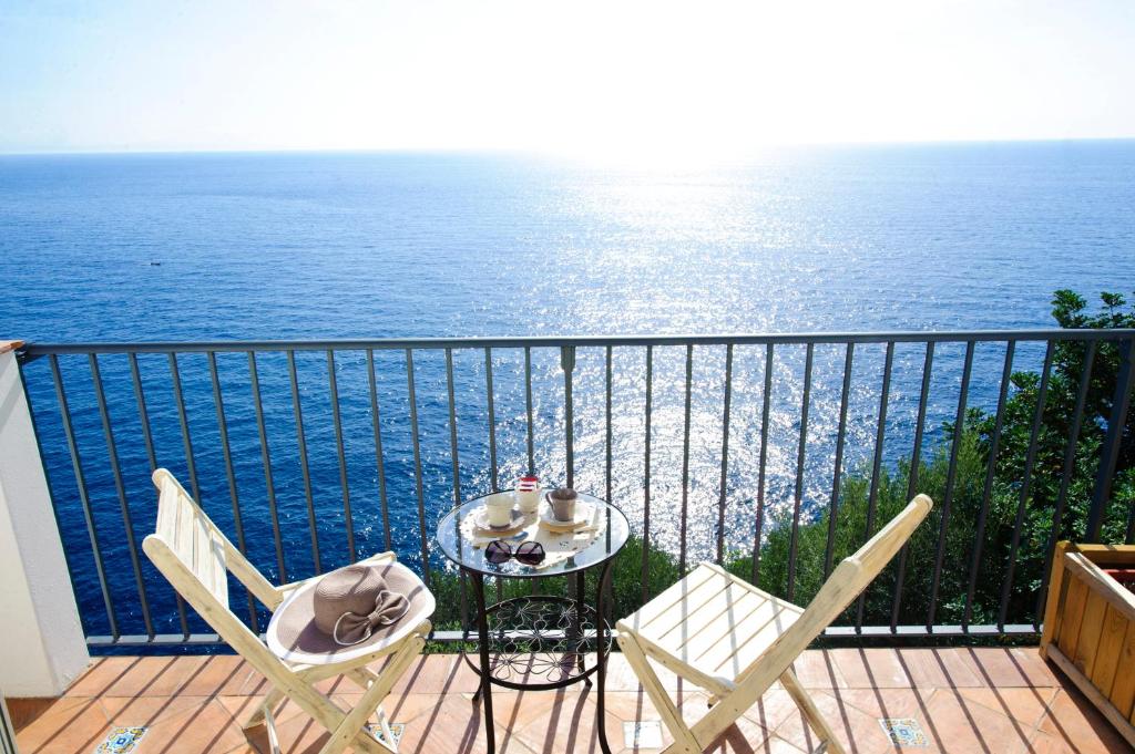 a table and chairs on a balcony with the ocean at La Maurella in Praiano