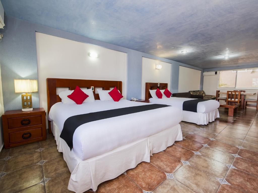 Habitación de hotel con 2 camas grandes y almohadas rojas en Suites de Reyes, en Irapuato