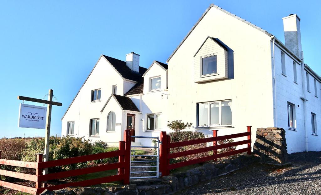 una casa blanca con una valla roja delante de ella en Wardicott, en Back