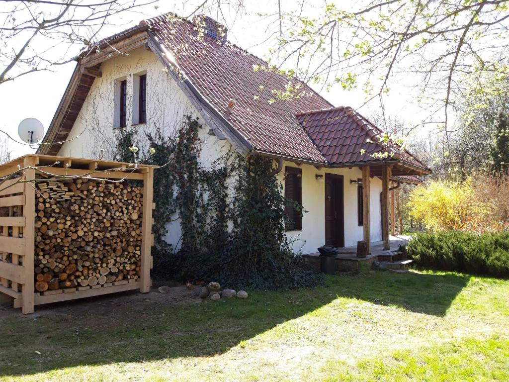 ein kleines weißes Haus mit einem Haufen Feuerholz in der Unterkunft Dom koło Rewala in Paprotno