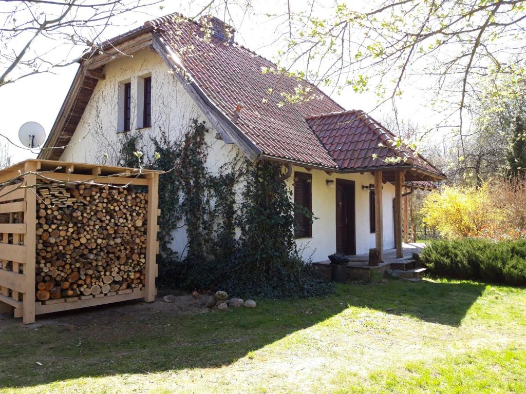 a small white house with a pile of fire wood at Dom koło Rewala in Paprotno