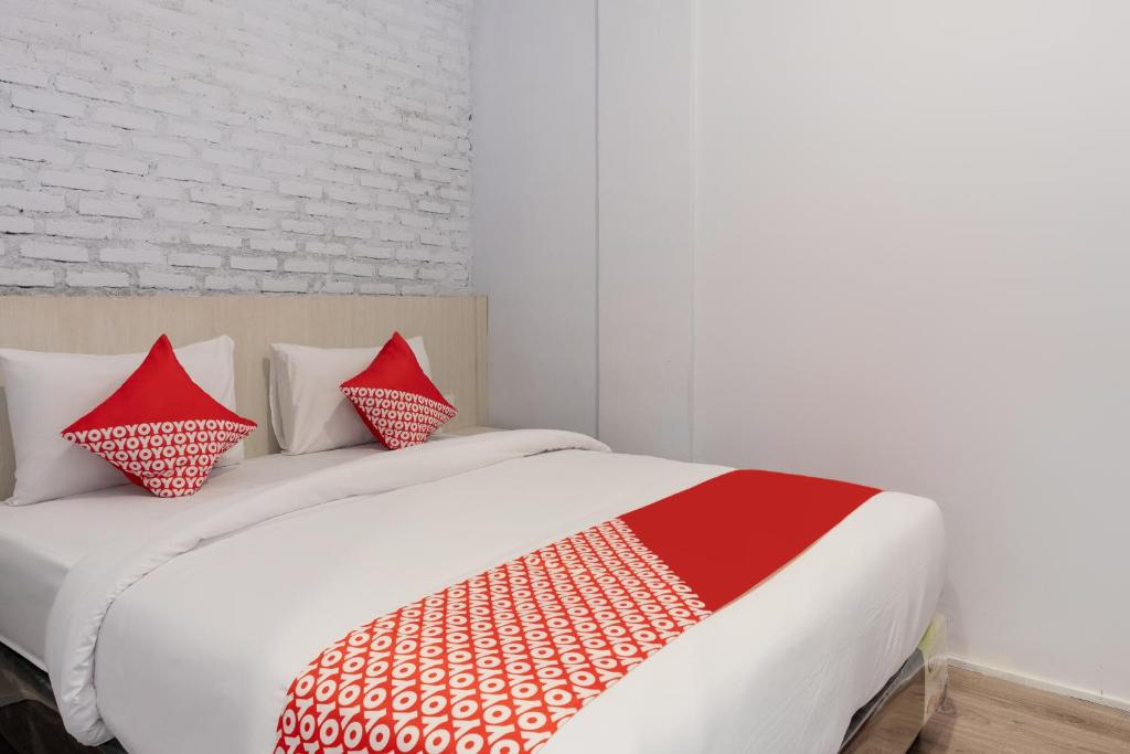 Super OYO 3150 Theodore Homestay في ميدان: غرفة نوم بسرير ومخدات حمراء وبيضاء