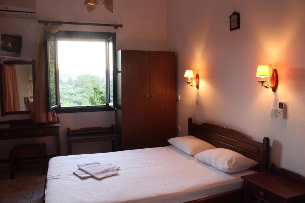 a bedroom with a bed with white sheets and a window at Theofilos Appartements in Livadi