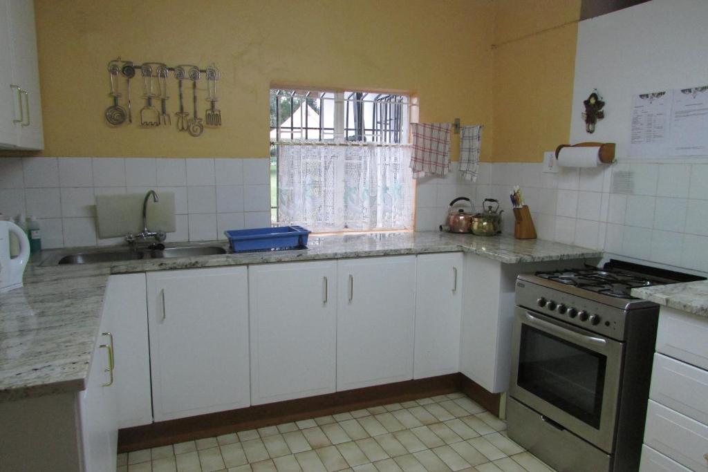 a kitchen with white cabinets and a stove top oven at Absolute Leisure Cottages in Machadodorp