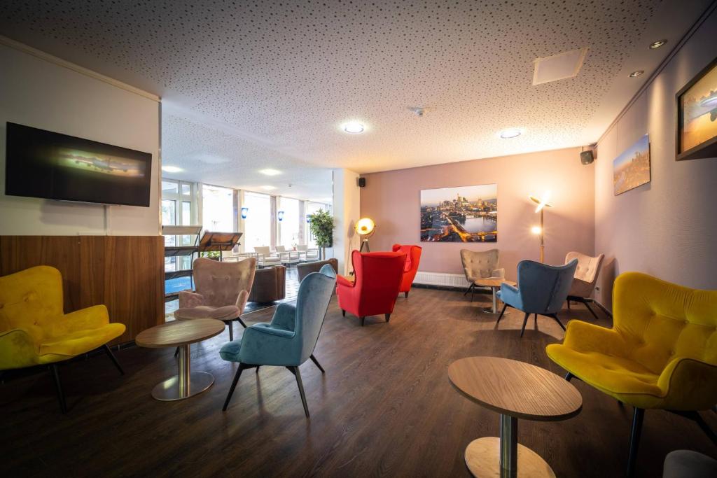 - une salle d'attente avec des chaises et des tables colorées dans l'établissement Anor Hotel & Conference Center Frankfurt Airport, à Mörfelden-Walldorf