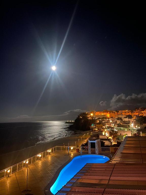 a view of the beach at night with the moon at XQ El Palacete in Morro del Jable