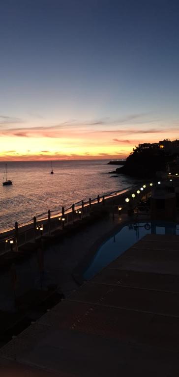 a sunset over the ocean with a fence and the water at XQ El Palacete in Morro del Jable