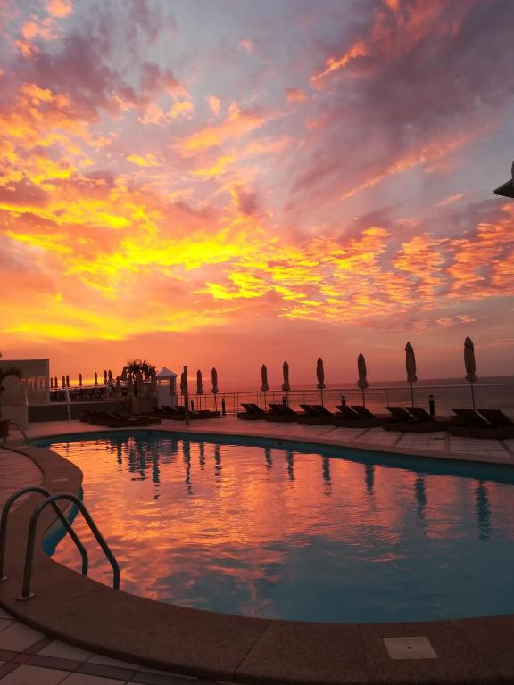 a swimming pool with a sunset in the background at XQ El Palacete in Morro del Jable