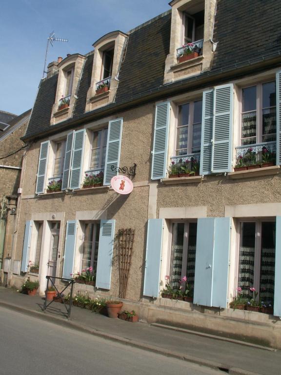 a building with blue shutters and flowers on the windows at Chambre d&#39;hôtes - Dodo et tartines in Bayeux