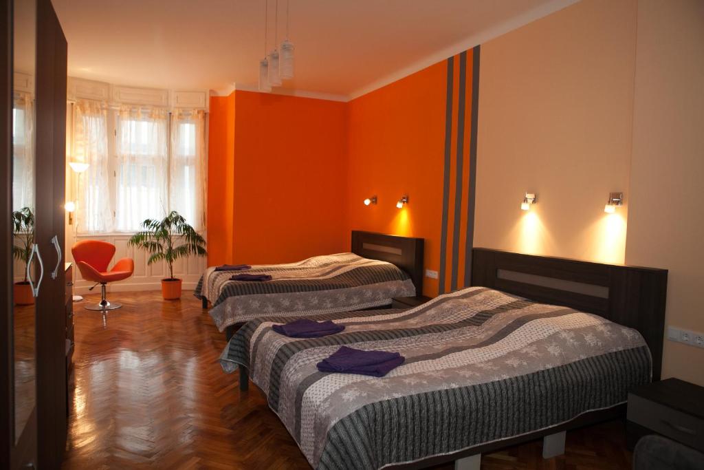 3 camas en una habitación con paredes de color naranja en Buda Trió Apartments, en Budapest