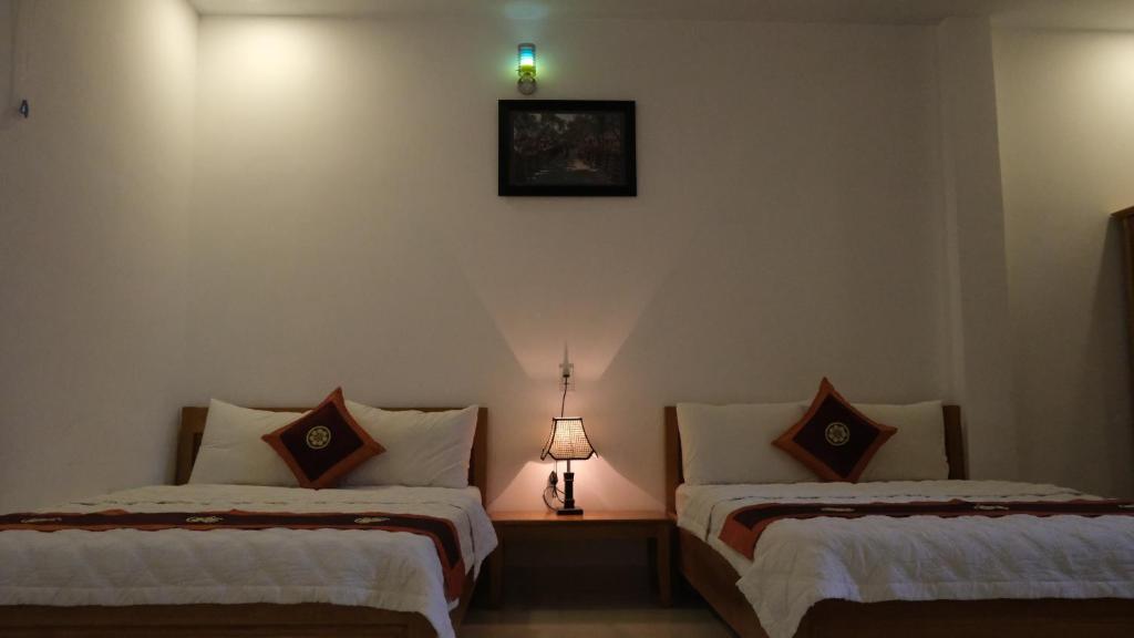 Cette chambre comprend 2 lits et une lampe murale. dans l'établissement Khách sạn Hiệp Thạnh, à Buôn Ma Thuột