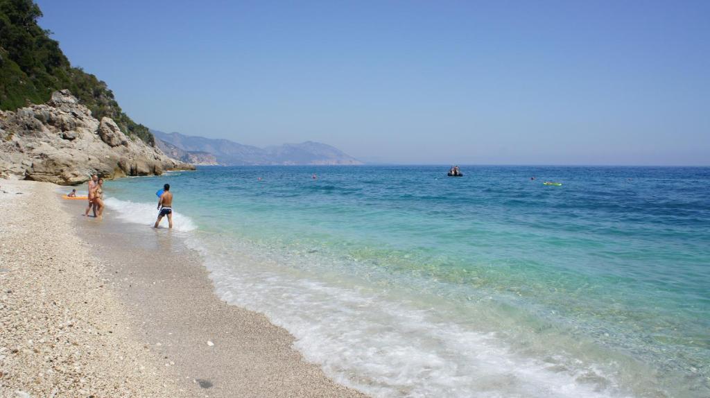 two people walking on the beach with their surfboards at Casa Turusele in Santa Maria Navarrese