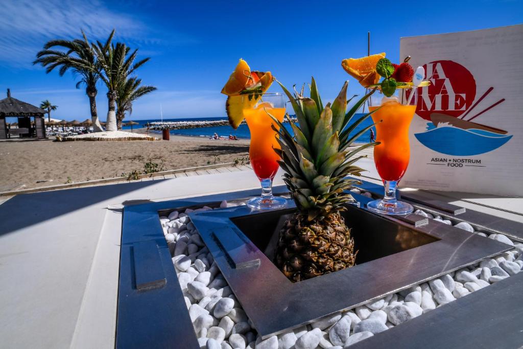 a table with two cocktails and a pineapple on a beach at Gran Hotel Guadalpín Banus in Marbella